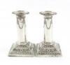 A pair of late-Victorian silver dwarf candlesticks, by Thomas Bradbury, London 1899, the columns with medallion and swag decoration, on raised square bases with foliate decoration, height 12cm. (2)