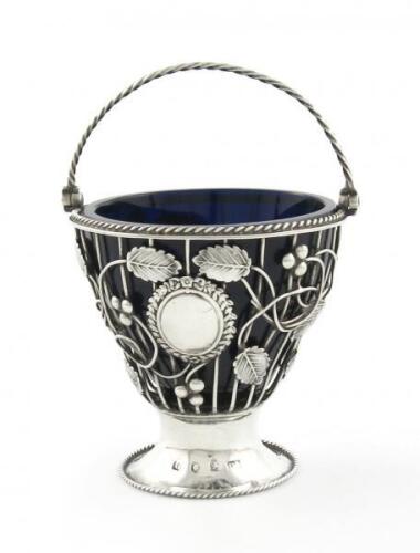 A George III silver swing-handled sugar basket, by Daniel Bates, London 1773, circular wire-work form, rope work borders and swing-handle, blue glass liner, height 8.5cm, approx. weight 3oz.
