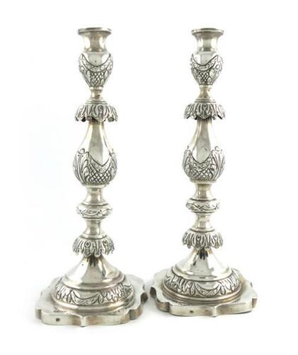 A large pair of silver Sabbath candlesticks, probably by Morris Salkind or Morris Sternberg, London 1915, baluster form, embossed decoration, lacking drip pans, on a shaped square base, height 36cm, approx. weight 32.3oz. (2)