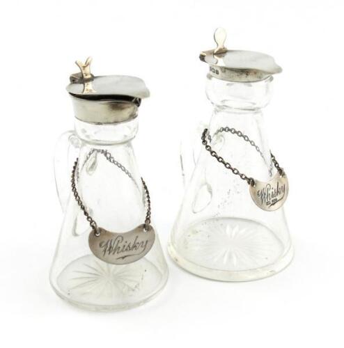Two similar silver-mounted whisky tots, one by Levi and Salaman, Birmingham 1923, one by Hukin and Heath, Birmingham 1912, tapering conical form, plain mounts, with two whisky labels. (4)