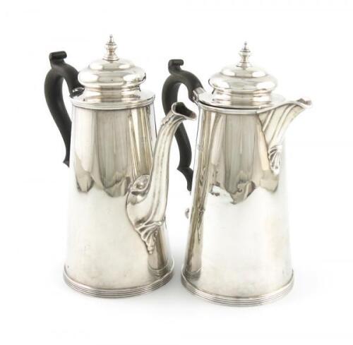 A pair of silver café au lait pots, by H. Woodward and Co, London 1910, tapering circular form, scroll handles, domed hinged covers with knop finials, height 20cm, approx. weight 28oz. (2)