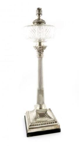 An Edwardian silver oil lamp, by Mappin and Webb, Sheffield 1902, Corinthian column form, on a stepped raised square base with foliate corners and a gadroon border, with a circular glass oil holder, later drilled for electricity, on a wooden base, height 