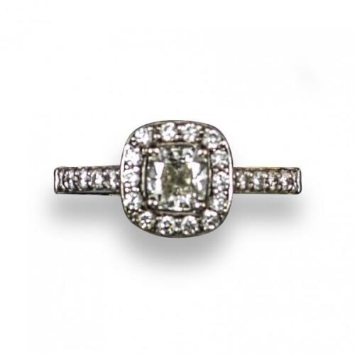 A diamond cluster ring, the central cushion-shaped diamond weighs 0.70cts and is set within a surround of circular-cut diamonds and diamond-set shoulders in white gold, with laser inscription to the girdle corresponding to the GIA certificate, size M 1/2,
